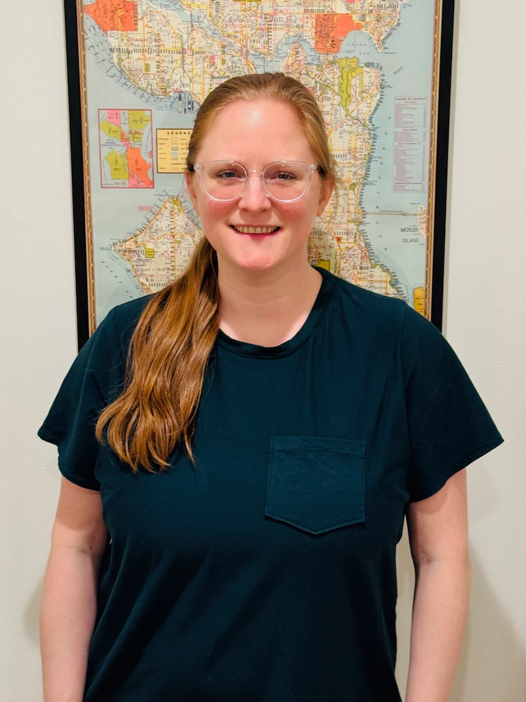 Me wearing a dark teal short-sleeved t-shirt. The t-shirt has a breast pocket on it, and the fabric pulls a little bit at the collar—you can tell it is homemade.