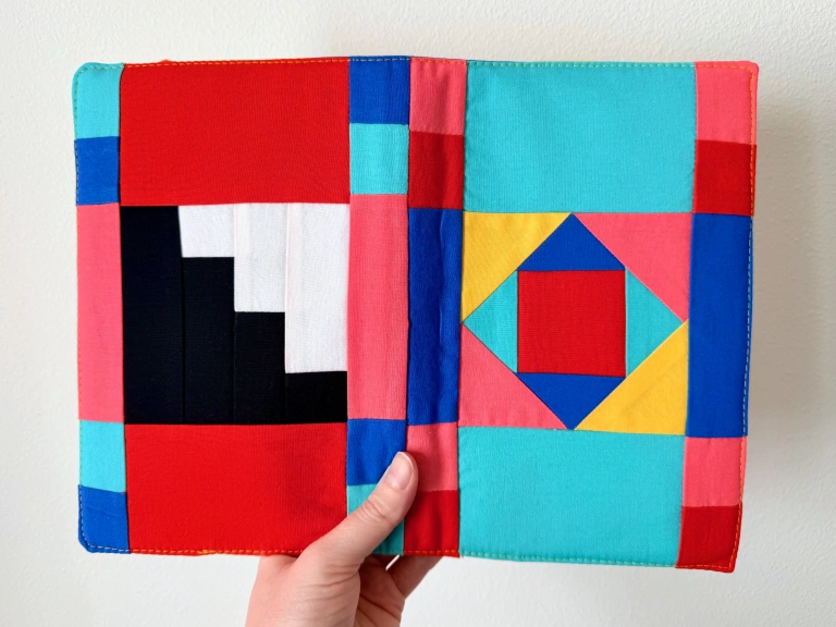 A cotton patchwork fabric cover in red, pink, yellow, cobalt blue, teal, and a bit of black and white