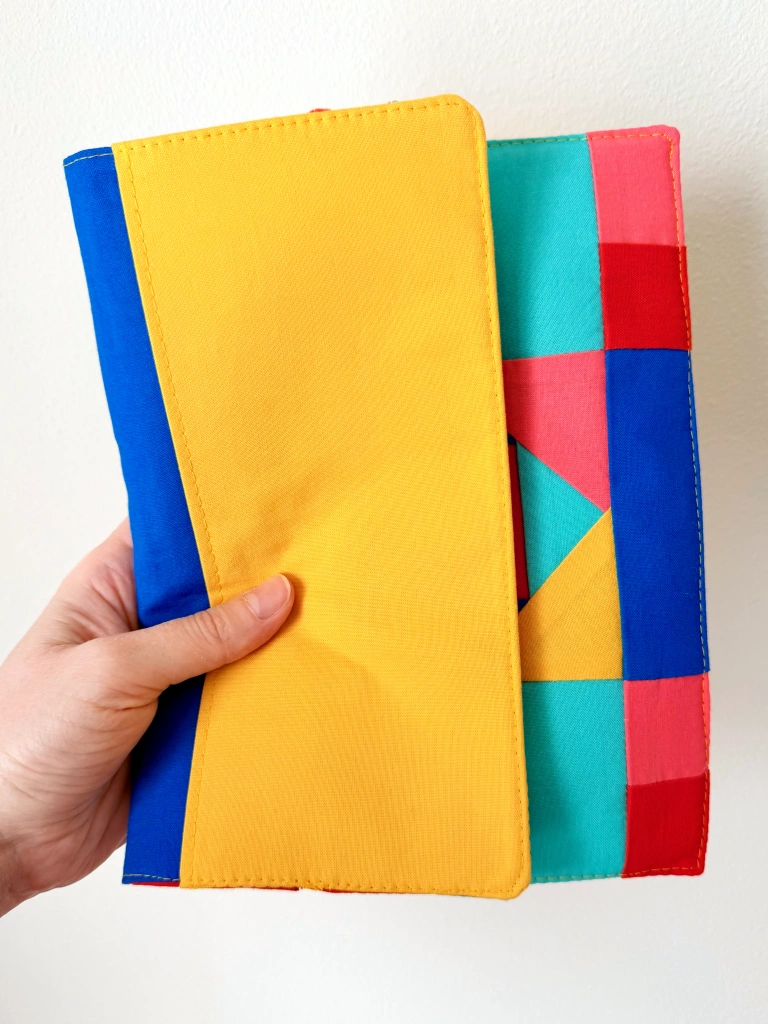 My hand holding the cover folded back to show a yellow and blue interior.