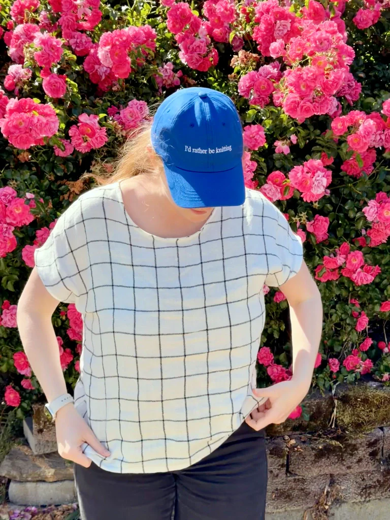 My head is down as I'm adjusting the shirt, and you can see that my cobalt blue baseball cap says I'd rather be knitting