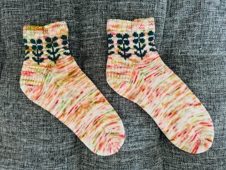 The pair of socks lying on a medium-grey tufted couch