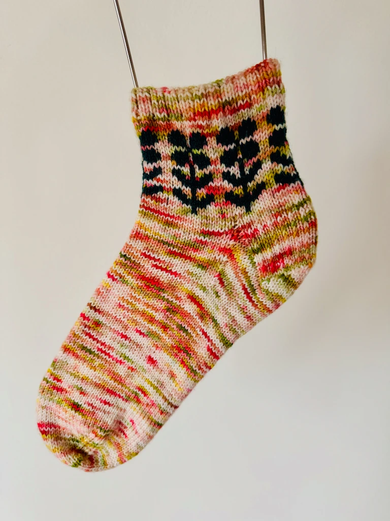 A single of the flower socks hanging on a wire sock blocker