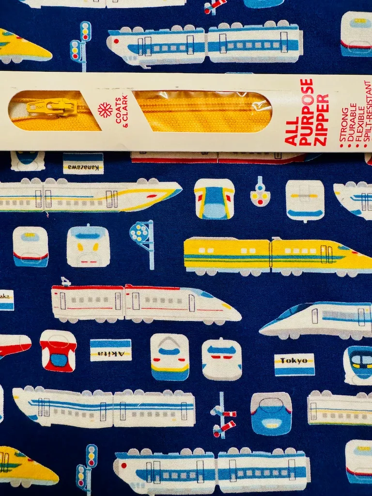 A closeup of the shinkansen fabric, with the packaged yellow zipper laid on top of it