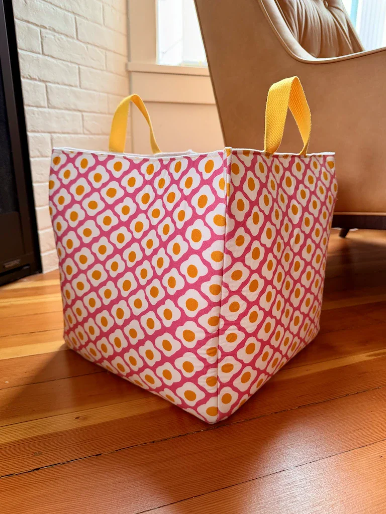 Another copy of the cube, this time with yellow handles, and a graphic print of fried eggs on a pink background